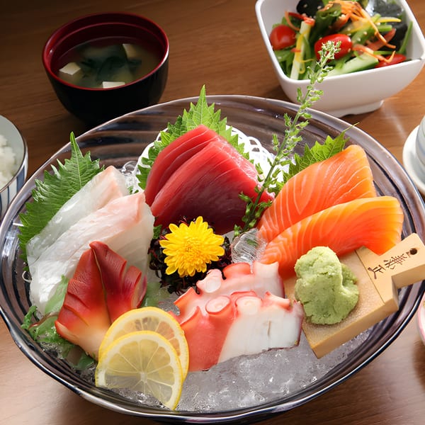 A large platter of fresh sashimi, including tuna, salmon, octopus, and clam, served on ice.