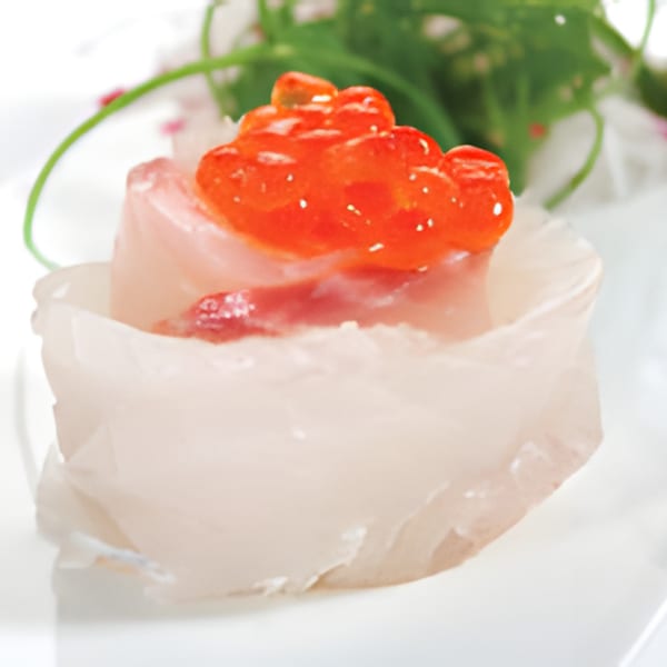 Delicate white fish sashimi, shaped like a flower, topped with bright orange salmon roe.