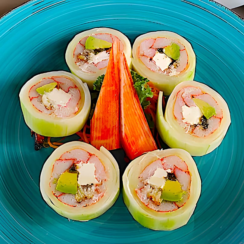 Six sushi rolls with shrimp, avocado, and cream cheese, garnished with crab sticks on a blue plate.