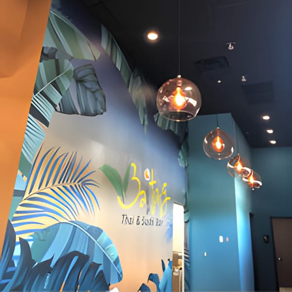 Interior of BAITONG Thai & Sushi Bar with tropical leaf mural and hanging glass pendant lights.